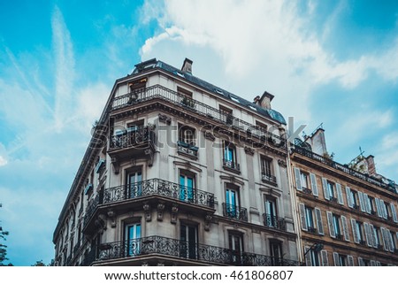 Elegant facade with window gates on old European apartment building under blue sky with scattered clouds
