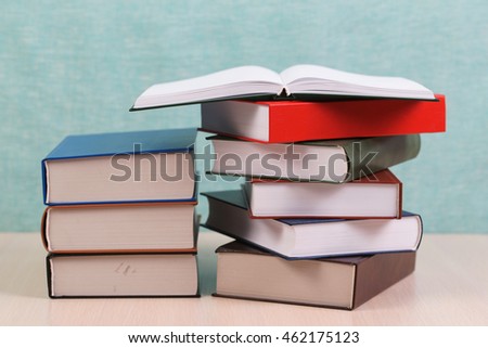 Open book, stack of hardback books on wooden table. Back to school. Copy space.