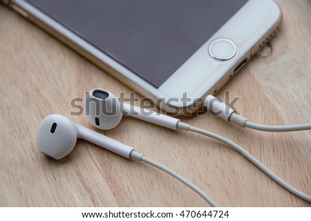 Smartphone and earphones on wood background