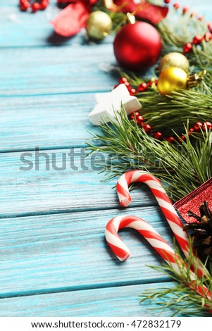 Christmas tree branch with baubles, candies on blue wooden table