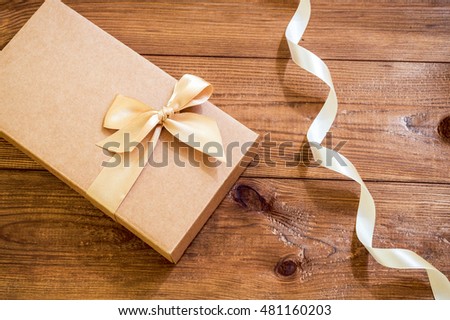 Vintage gift box with gold bow on old wooden background