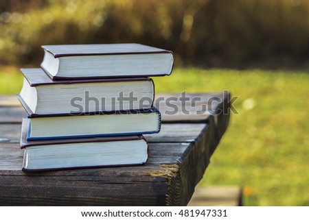 Pile of closed books on wooden table.
