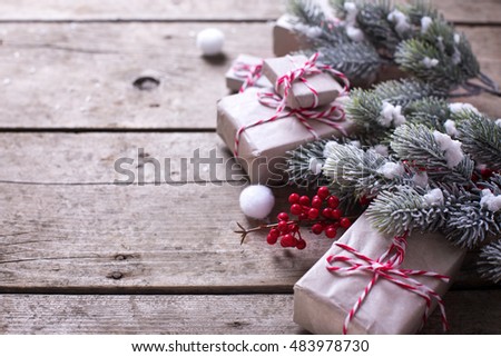Wrapped christmas presents, fur tree branches, red berries on aged wooden background. Selective focus is on berries. Place for text.
