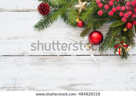 Christmas tree branch with decorations on white wooden table.