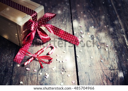 Christmas present with red ribbon on dark wooden background in vintage style 