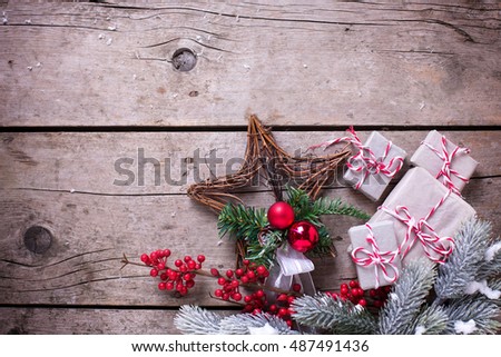Wrapped christmas presents, fur tree branches, red berries on aged wooden background. Selective focus. Place for text.