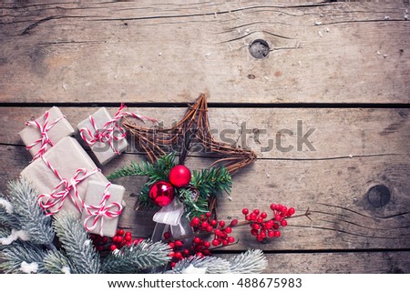 Wrapped christmas presents, fur tree branches, red berries on aged wooden background. Selective focus. Place for text. Toned image.