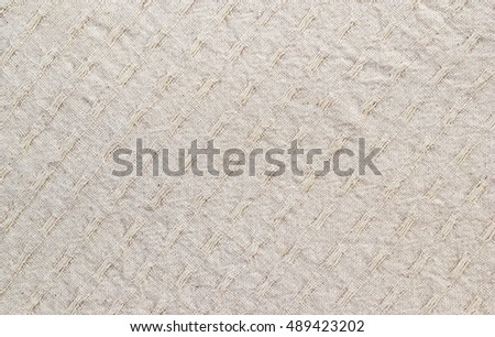 A close-up of beige fabric with extra loop of thread