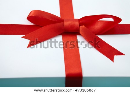 White gift box with red ribbon. Selective focus. Macro