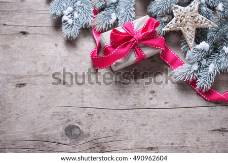  Christmas present in wrapped box,  star and branches fur tree on  vintage wooden background. Decorative christmas composition. Selective focus. Place for text.