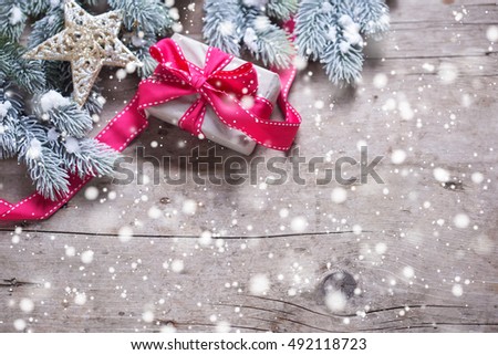  Christmas present in wrapped box,  star and branches fur tree on  vintage wooden background. Decorative christmas composition. Selective focus. Place for text. Drawn snow.