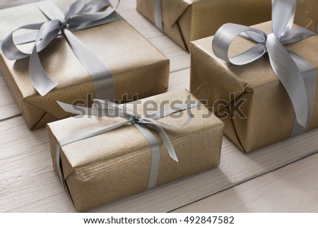 Gift boxes on white wood background. Presents in craft paper decorated with stylish elegant silver satin ribbon bows. Christmas and any other holidays concept