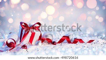 Gift Box And Baubles On Snow With Shiny Background
