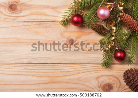 Corner of fir branches with Christmas decorations on a light wooden background