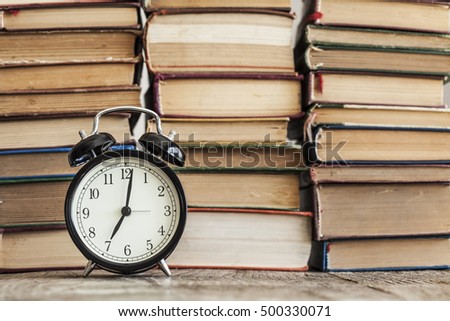 Pile of books with o'clock on desk