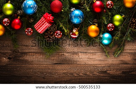 Merry Christmas Frame with real wood green pine, colorful baubles, gift boxe and other seasonal stuff over an old wooden aged background