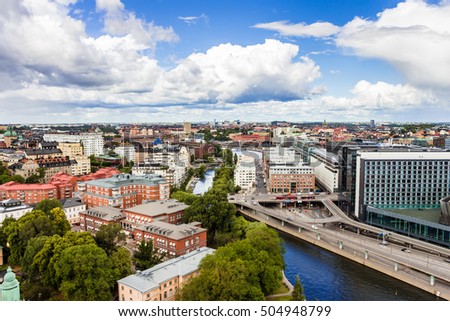 View of skyline Stockholm, Sweden from above. View on Kungsholmen from observation deck in Town Hall. Space for your text. Street, contemporary buildings, green trees, channel. Day with large clouds.