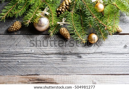 Christmas background. Green Fir tree branches with pine cones, gold snowflakes, ball on wooden background. Copy spase