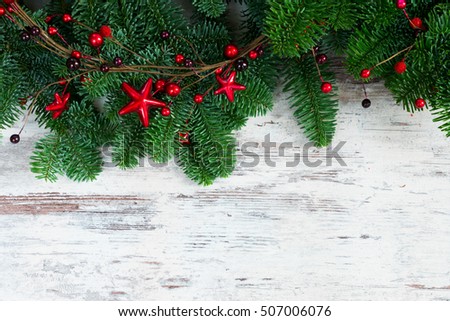 christmas fresh evergreen tree branches with red berries and stars garland on wood