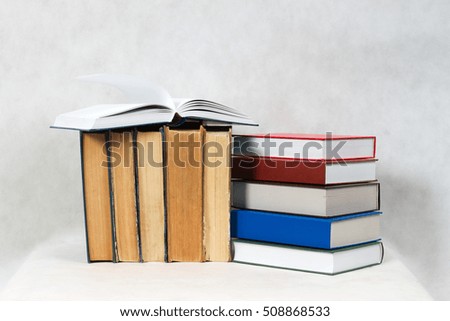 Open book, stack of hardback books on table. Back to school. Copy space.