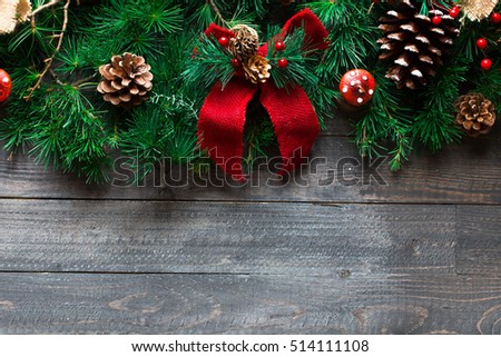 Merry Christmas Frame with real wood green pine, colorful baubles, knots with berries and other seasonal stuff over an old wooden aged background