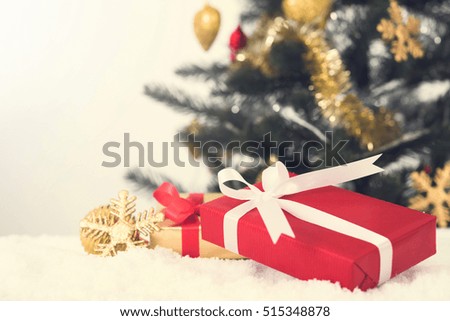 Gift boxes and Christmas ornaments on the snow with blur Christmas tree background
