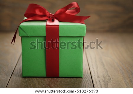 green paper gift box gift box with lid and red ribbon bow on wood table with copy space