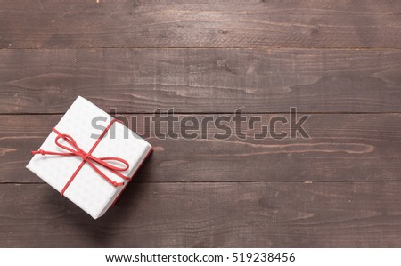 White and red gift box is on the wooden background with empty space.