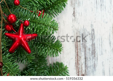 christmas fresh evergreen tree branches with red stars ans berries on wooden background close up