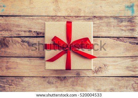 Brown gift box on wooden background. Gift box with red ribbon on wood background with space.