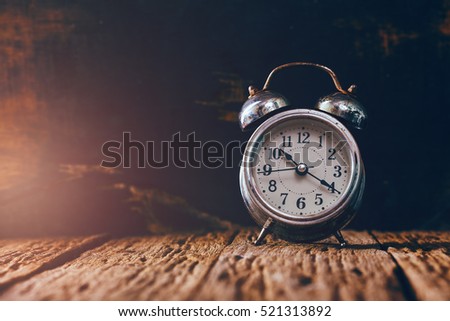 Dark background with retro alarm clock on table