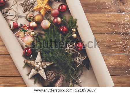 Prepare for christmas eve or other winter holidays. Xmas decorations, fir tree and garlands concept background, top view on wood. Ornaments, present packaging paper, stars, gingerbread and balls
