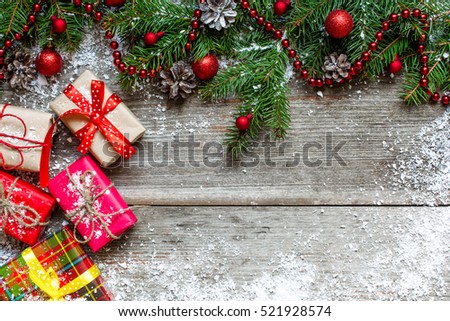 christmas gift boxes with fir tree, pine cones and red decorations on wooden table background covered with snow