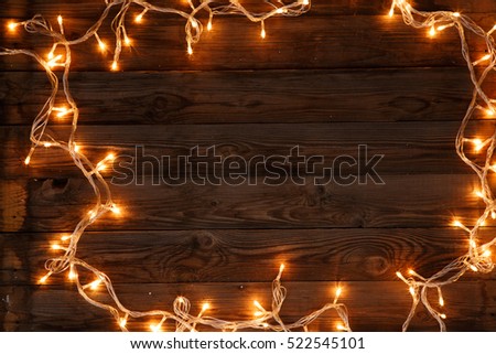 Dark brown wooden background with shining garland on the frame