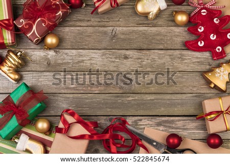 Christmas ornaments, gifts, scissors and wrapping paper on a gray wooden background.