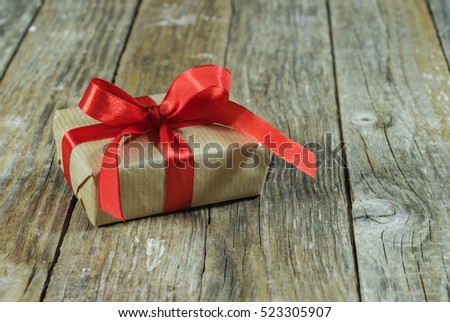 Gift box with red bow ribbon on wooden table background