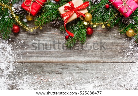 christmas fir tree with gift boxes, pine cones and decorations on rustic wooden background covered with snow with copy space