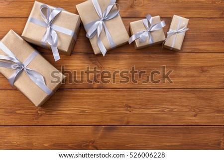Presents for any holiday concept. Gift boxes frame, top view with copy space on wood table background. Border of gold packages with silver satin ribbons for christmas, valentine day or birthday