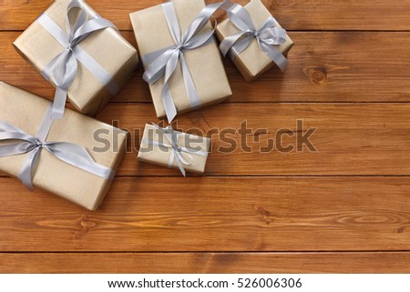 Presents for any holiday concept. Gift boxes frame, top view with copy space on wood table background. Border of gold packages with silver satin ribbons for christmas, valentine day or birthday