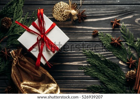 stylish christmas flat lay presents with red ribbon and golden ornaments on rustic  wooden background with green branches. space for text. seasonal greetings for winter holidays card concept 