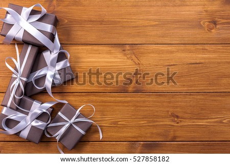 Presents for any holiday concept. Gift boxes frame, top view with copy space on wood table background. Border of packages with satin ribbons for christmas, valentine day or birthday