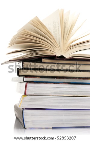 Open book on stack of various books against white background.