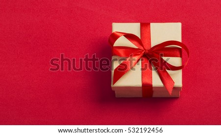 Gift kraft square box with a red ribbon on a red background