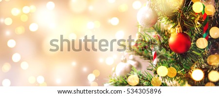 Closeup of red bauble hanging from a decorated Christmas tree with bokeh, copy space, Xmas holiday background.