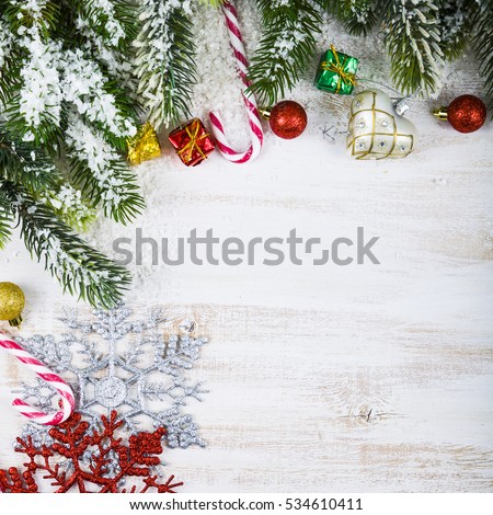 Christmas decorations, gifts and fir branches in the snow on a wooden table. Christmas border closeup.