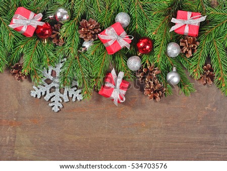 Silver and red Christmas decorations and spruce branch and cones on a wooden background