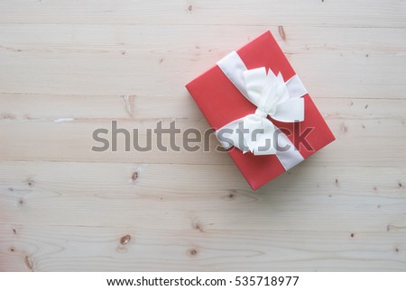 Red gift box with white ribbons on wooden floor concept for Happy new year and Christmas concept