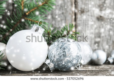 Silver and white christmas ornaments, xmas tree on rustic wood background with blurred snow. Merry christmas greeting card. Winter holiday theme. Happy New Year. Space for text.