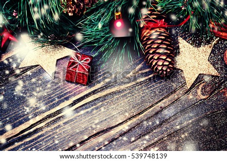 		Christmas fir tree with decoration on dark wooden board - Christmas background with a red ornament, gift boxes, pine and snowflakes  with copyspace.
