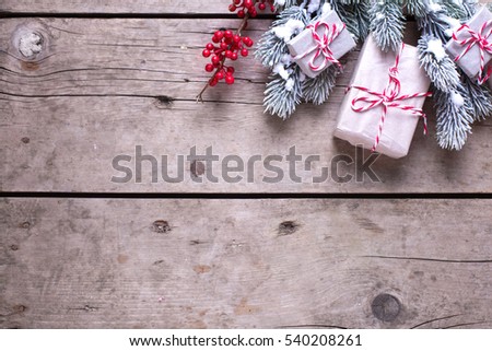 Christmas border. Wrapped christmas presents, fur tree branches, red berries on aged wooden background. Selective focus. Place for text.
